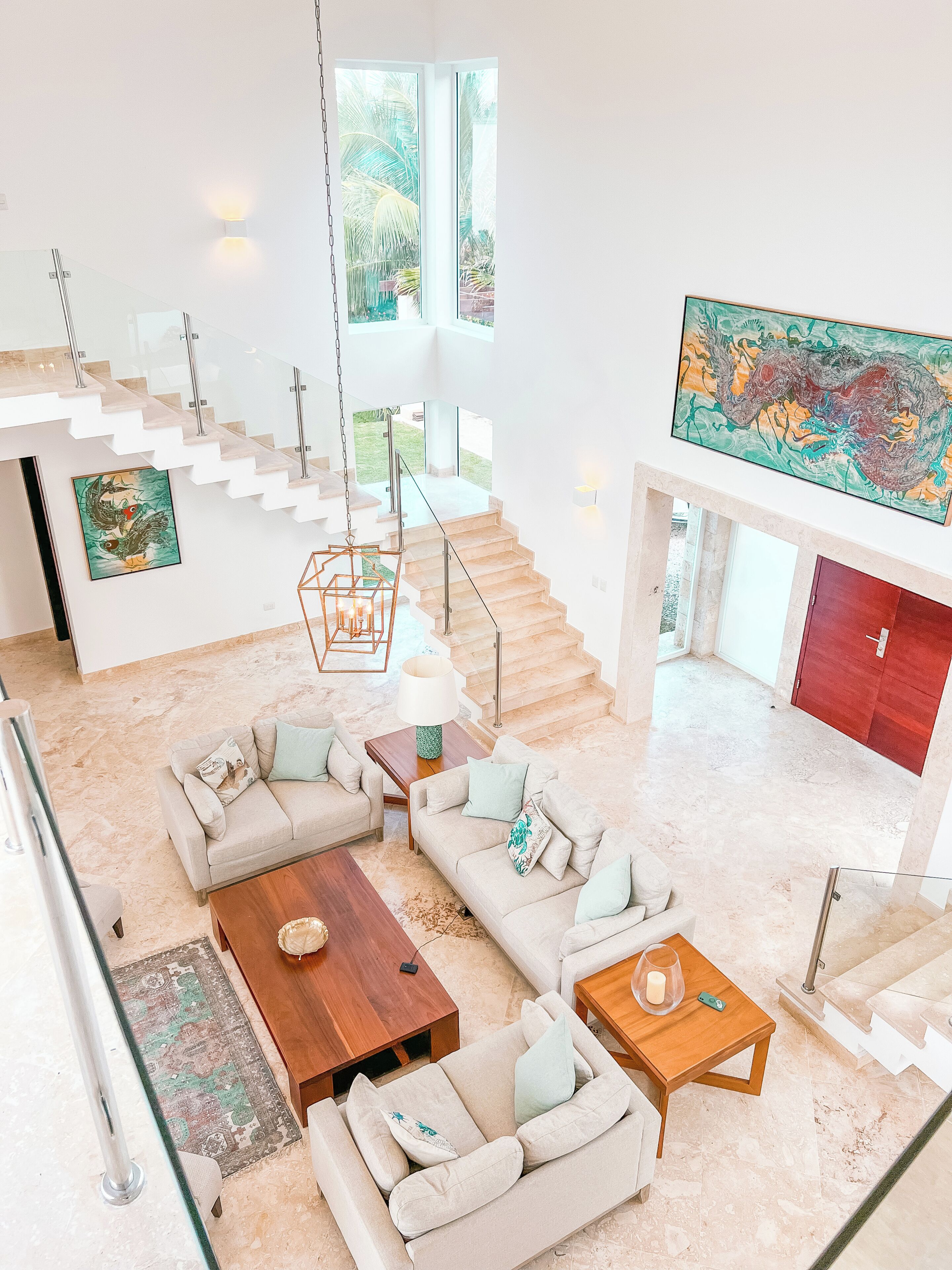 A spacious living area with a high ceiling, a staircase, and a large painting.