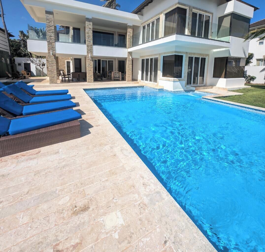 A modern two-story house with a swimming pool, outdoor seating, and a well-maintained lawn.