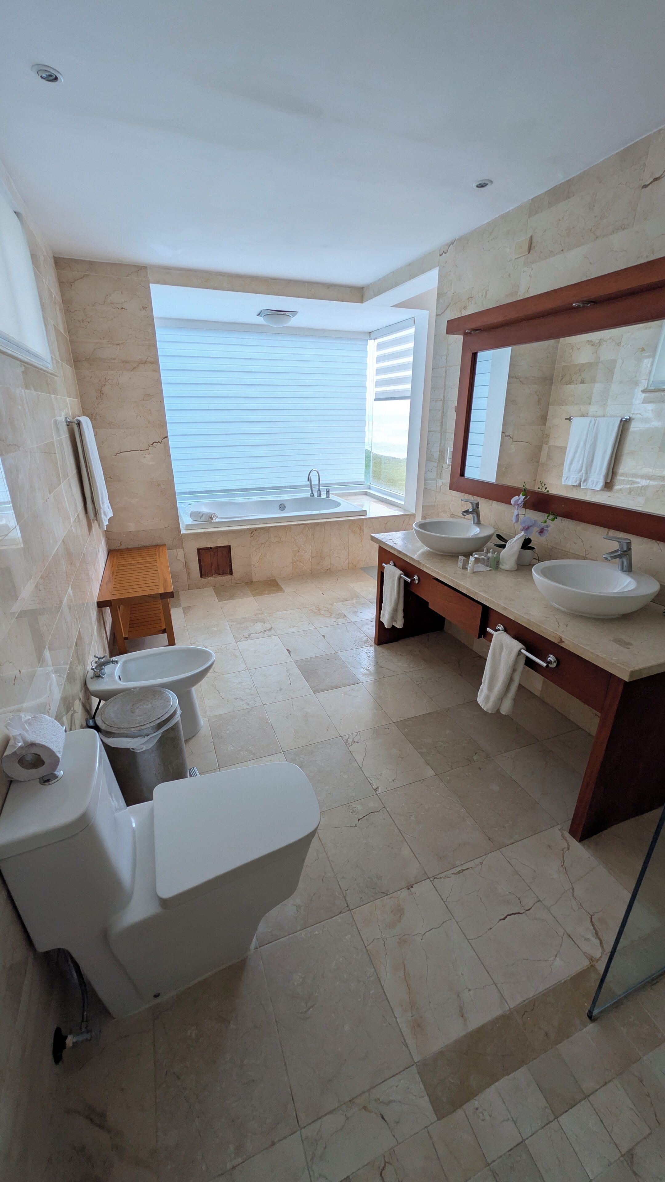 Een moderne badkamer met toilet, bidet, wastafel en bad.