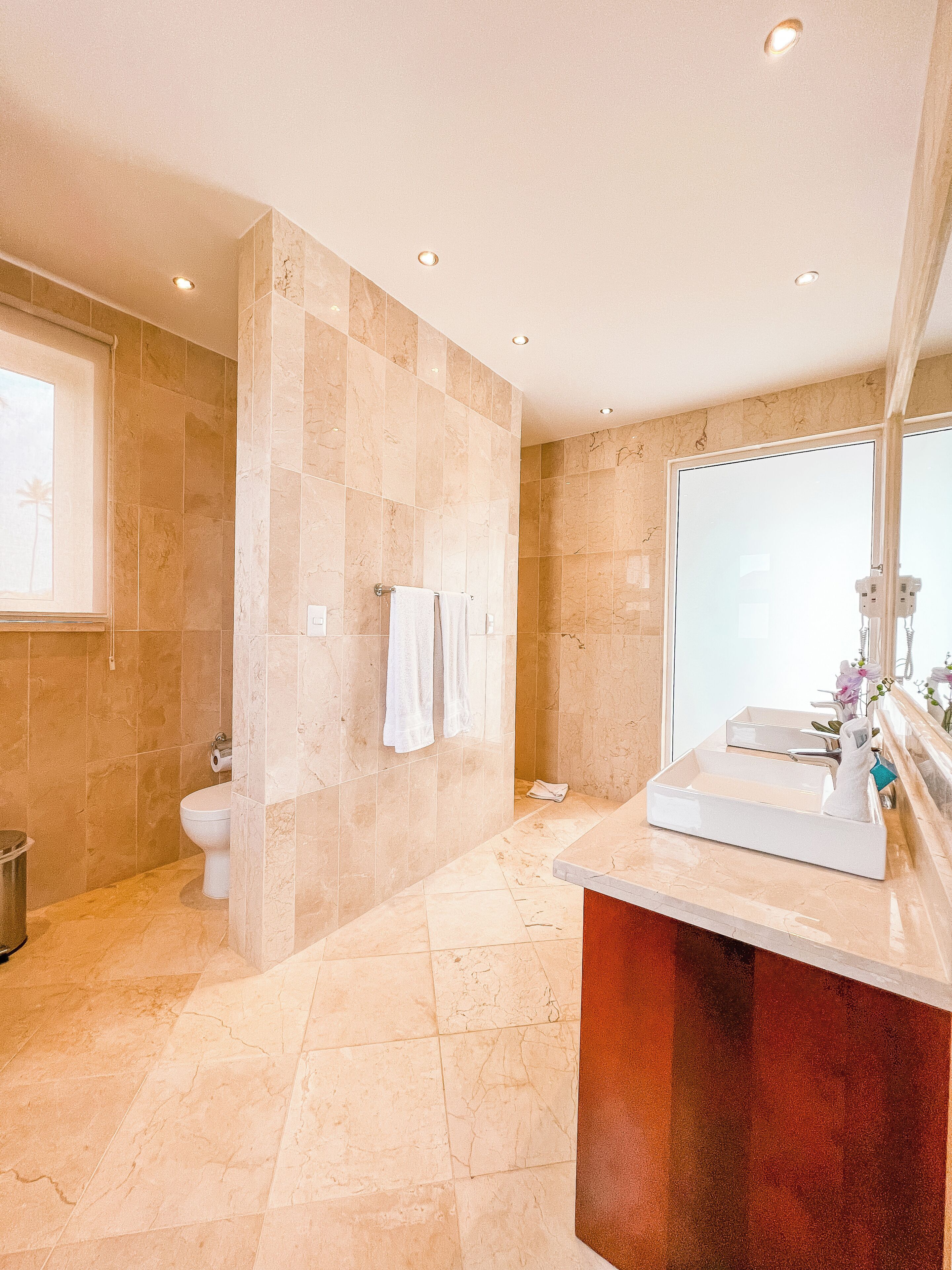 A bathroom with a marble floor, a white sink, and a large mirror.