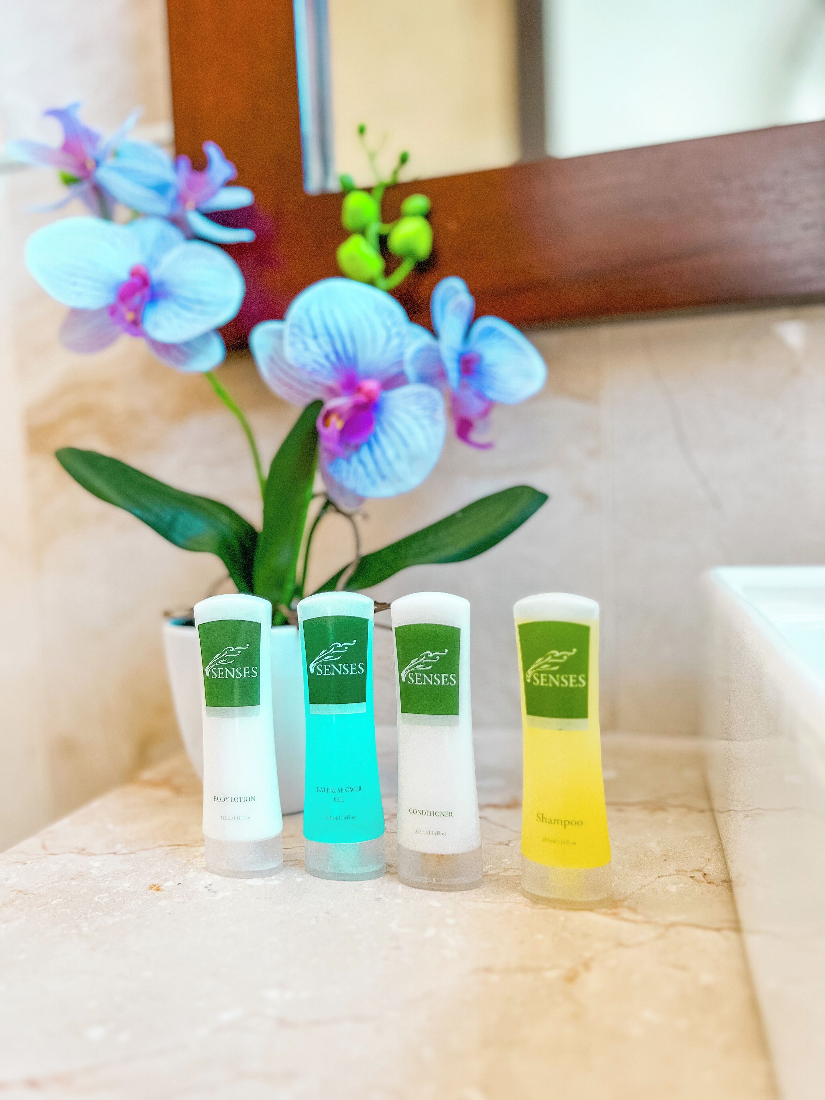 Four bottles of Senses body care products on a marble countertop.