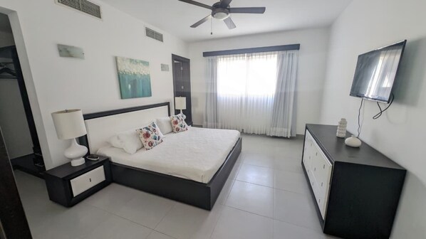 A modern hotel room with a large bed, a TV, a ceiling fan, and a window with curtains. - Peninsula Esmeralda Luxury Hotel & Villas (Puerto Plata)