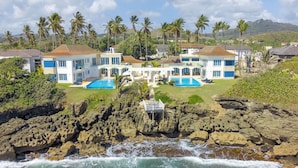 A coastal resort with multiple swimming pools, a rocky shoreline, and palm trees. - Peninsula Esmeralda Luxury Hotel & Villas (Puerto Plata)