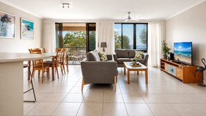 Amplia sala de estar con comedor, sofás, televisor y un balcón con vistas.