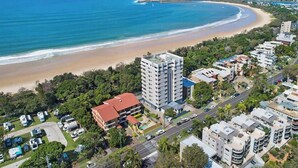 A coastal area with a beach, a tall hotel building, and surrounding residential buildings. - Lamer 1 Beach Access Courtyard Apt (Maroochydore)