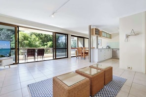 A modern interior with a dining area, kitchen, and large sliding glass doors to a balcony. - Lamer 5 Beachfront Apt Mooloolaba (Maroochydore)