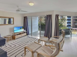Ein modernes Wohnzimmer mit Flachbildfernseher, einer Couch, einem Couchtisch und einem Essbereich mit Stühlen.