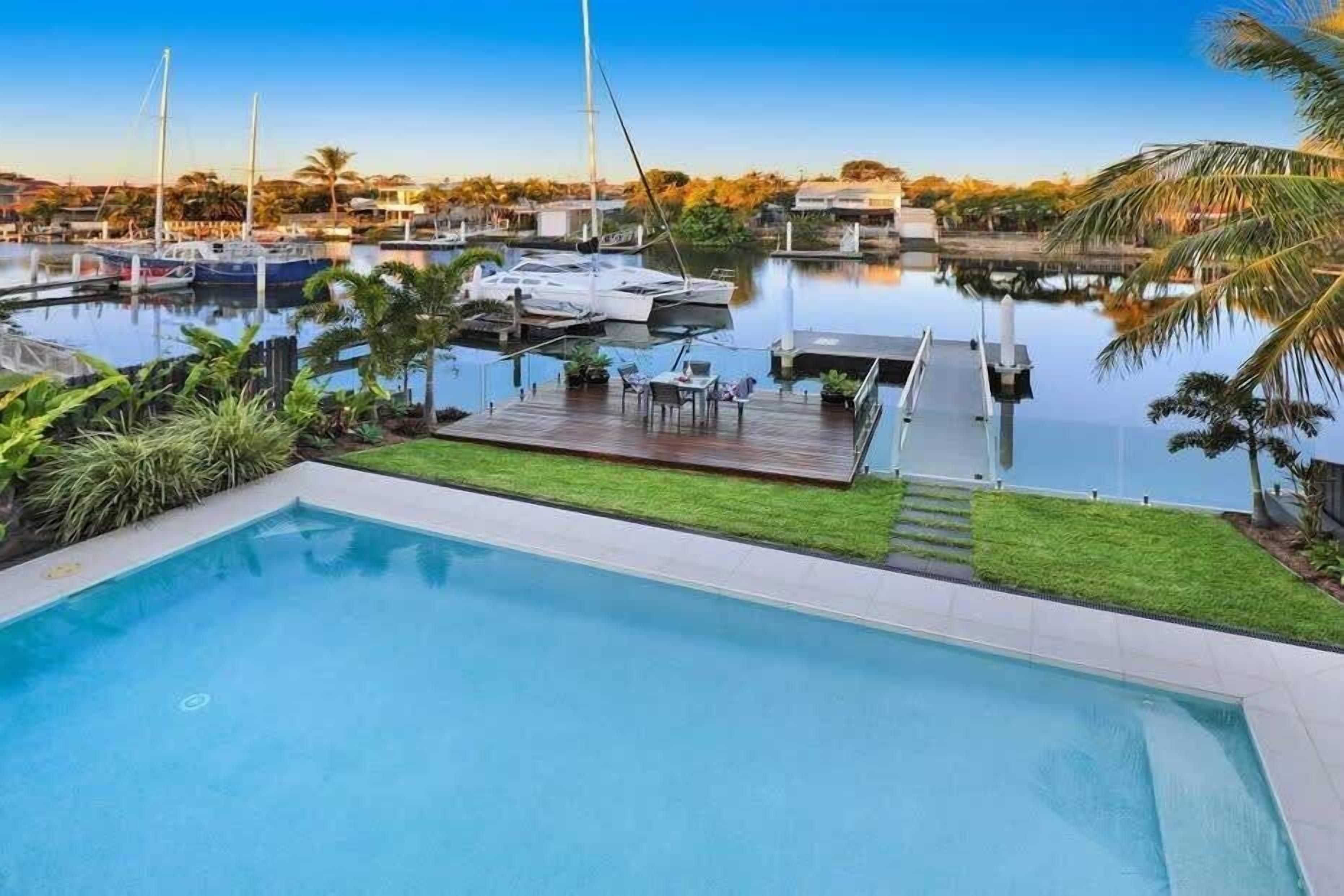 A swimming pool with a dock and boats in the background.