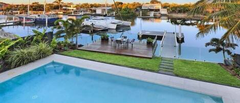 A swimming pool with a dock and boats in the background.