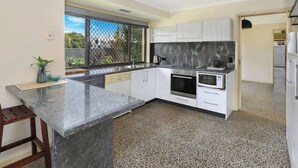 A modern kitchen with a marble countertop, stainless steel appliances, and a large window providing natural light. - Naroo 7 Central Mooloolaba Stay (Mooloolaba)