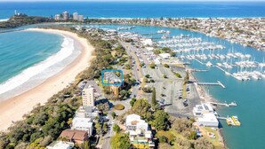 An aerial view of a coastal area with a marina, beach, and residential buildings. - Illawong 1 Beachfront Doorstep Apt (Mooloolaba)