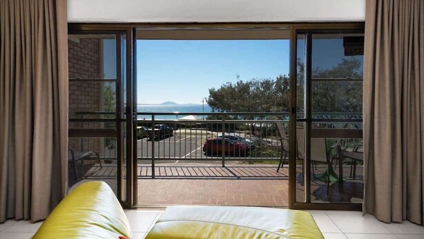 Ein Balkon mit Blick auf das Meer und geparkte Autos.