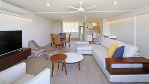 Un salon moderne doté d’un téléviseur à écran plat, d’un canapé, d’une table à manger avec des chaises et d’un ventilateur de plafond.