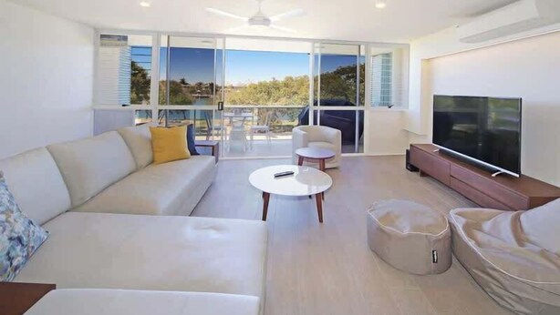 Un salon moderne avec un canapé, une table basse, un téléviseur et un balcon offrant une vue agréable.