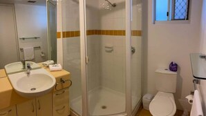 Une salle de bain équipée d’une douche, de toilettes, d’un lavabo et d’une cabine de douche en verre.