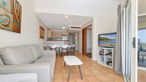 Un salon avec un canapé, une table à manger et des chaises, un téléviseur et un balcon avec vue.