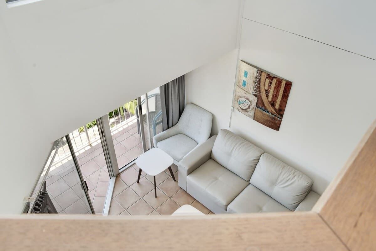 A modern interior with a sofa, a small table, and a wall with a decorative piece.