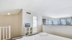 Une chambre d’hôtel avec un lit, une télévision, une fenêtre avec des rideaux et une vue sur les arbres.