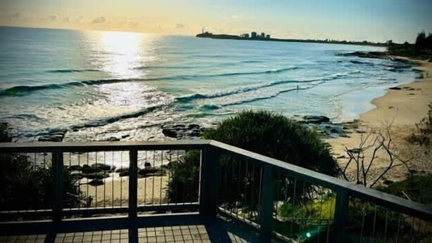 Une vue sur la côte, avec une balustrade, l’océan et des bâtiments situés au loin.