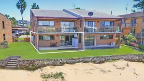 Une maison à deux étages avec un balcon, un garage et un mur en pierre.