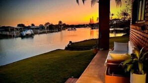 Une terrasse offrant une vue sur un plan d’eau et sur le coucher du soleil.