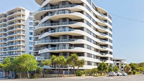 A modern multi-story building with balconies, a clear sky, and a street view. - Breeze 801 Luxury Mooloolaba Apt with Ocean Views (Mooloolaba)