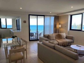 A modern living room with a sofa, a glass table, and a view of the ocean. - Breeze 801 Luxury Mooloolaba Apt with Ocean Views (Mooloolaba)