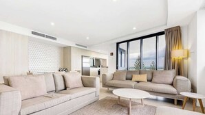 A modern living room with two sofas, a coffee table, and a large window with a view. - Breeze 801 Luxury Mooloolaba Apt with Ocean Views (Mooloolaba)