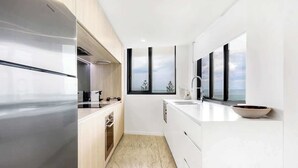 A modern kitchen with a large window, a built-in oven, and a white countertop. - Breeze 801 Luxury Mooloolaba Apt with Ocean Views (Mooloolaba)