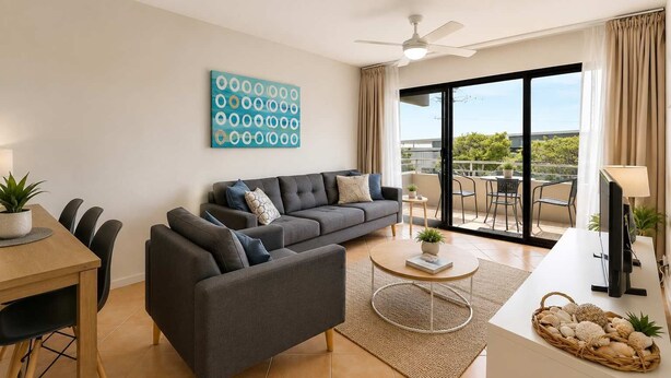 Una sala de estar moderna con un sofá gris, una mesa de comedor con sillas, una mesa de centro y vistas al exterior a través de grandes puertas correderas.