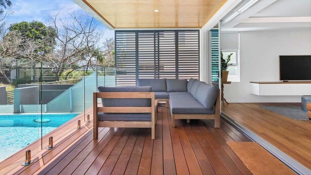 Ein moderner Außenbereich mit Holzterrasse, integriertem Sitzbereich und Pool.