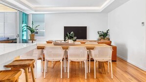 Ein modernes Wohnzimmer mit Essbereich, einem großen Flachbildfernseher und einer Couch.