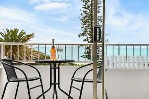 A balcony with a table and two chairs, overlooking a beach. - Bilgola 4 Beach View Apt (Alexandra Headland)