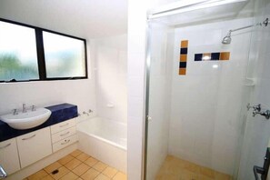 A bathroom with a sink, mirror, and bathtub.