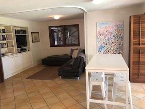Un salon avec un canapé, une table à manger et des chaises, un téléviseur et une bibliothèque.