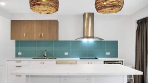 Una cucina moderna con mobili bianchi, zoccolo verde acqua e un'isola centrale con sgabelli.