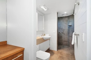Une salle de bain moderne avec un meuble-lavabo en bois, un lavabo blanc et un espace douche.
