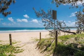 Une plage avec une clôture en bois, un panneau indicateur et une vue dégagée sur l’océan.