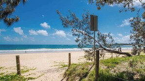 Una playa con una cerca de madera, un cartel y una vista despejada del océano.