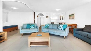Una sala moderna con dos sofás, una mesa de centro y un comedor con mesa y sillas.