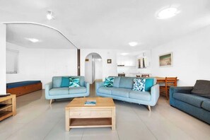 A modern living room with two sofas, a coffee table, and a dining area with a table and chairs. - Lahaina 7 Beachfront Mooloolaba Apt (Maroochydore)