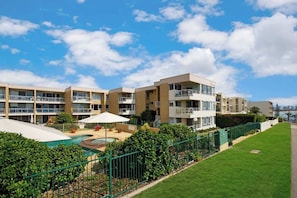 Un hôtel à plusieurs étages, doté de balcons, d’une piscine et d’une pelouse bien entretenue.