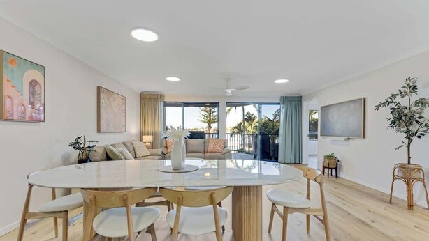 Uma sala de estar moderna com uma mesa de jantar redonda, sofás e uma grande janela com vista.