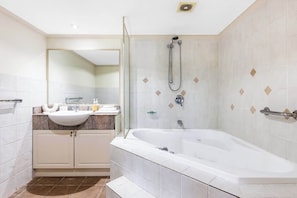 Un baño moderno con bañera, ducha, lavamanos y espejo.
