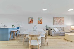 A modern living space with a round dining table, a sofa, and a kitchen area.