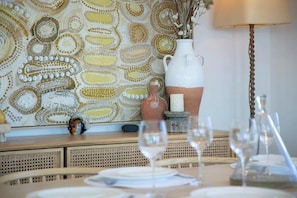 A dining table set with glasses, a white pitcher, and a decorative vase.