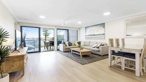 Un vaste espace de vie comprenant un canapé, une table basse et une table à manger, de grandes fenêtres et un balcon.