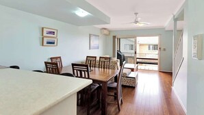 A dining area with a wooden table and chairs, a sofa, and a ceiling fan.