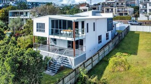 Ein modernes, zweistöckiges Haus mit Balkon, Treppe und einem eingezäunten Garten.