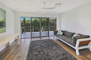Un salon moderne avec un canapé gris, un banc blanc et un grand tapis gris.